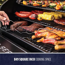 Large grill with 849 sq. in. cooking space, loaded with meats, corn, and veggies on two racks. Easy-access design.