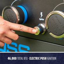 Close-up of a hand pressing an electric push ignition button on a grill with 46,000 BTU control knobs.