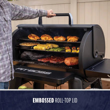 Black Pit Boss grill with embossed roll-top lid, cooking various meats and vegetables.