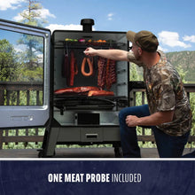 Outdoor smoker with open door, meats hanging inside, man checking food; includes one meat probe.