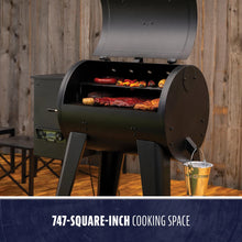 Black pellet grill with 747-square-inch cooking space, cooking assorted meats and vegetables.