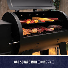 Black grill with 840-square-inch cooking space, featuring meats and vegetables.