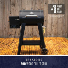 Black FB2 Series 500 wood pellet grill with control panel, sturdy legs, wheels, and side bucket, set on a wooden deck.