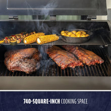 Black grill with 740-square-inch cooking space, smoking meats and vegetables.