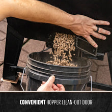 Black pellet grill with convenient hopper clean-out door.