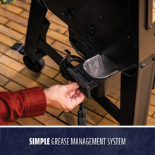 Outdoor grill with a removable grease tray for easy cleaning. Hand shown pulling out the tray. Simple grease management sy...