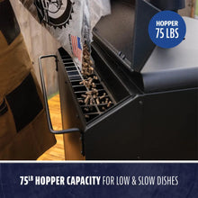 Large black pellet grill hopper with 75 lb capacity, shown being filled with wood pellets. Ideal for slow cooking.