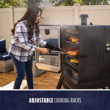 Outdoor smoker with adjustable cooking racks, glass door, and digital controls. Woman grilling meat and corn on patio.